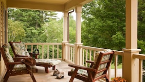 A wooden porch with two rocking chairs, a bench, and a pair of binoculars. - The Waterford Inne (Waterford)