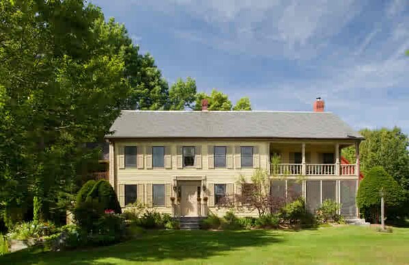 A two-story house with a front porch, a chimney, and a well-maintained lawn. - The Waterford Inne (Waterford)