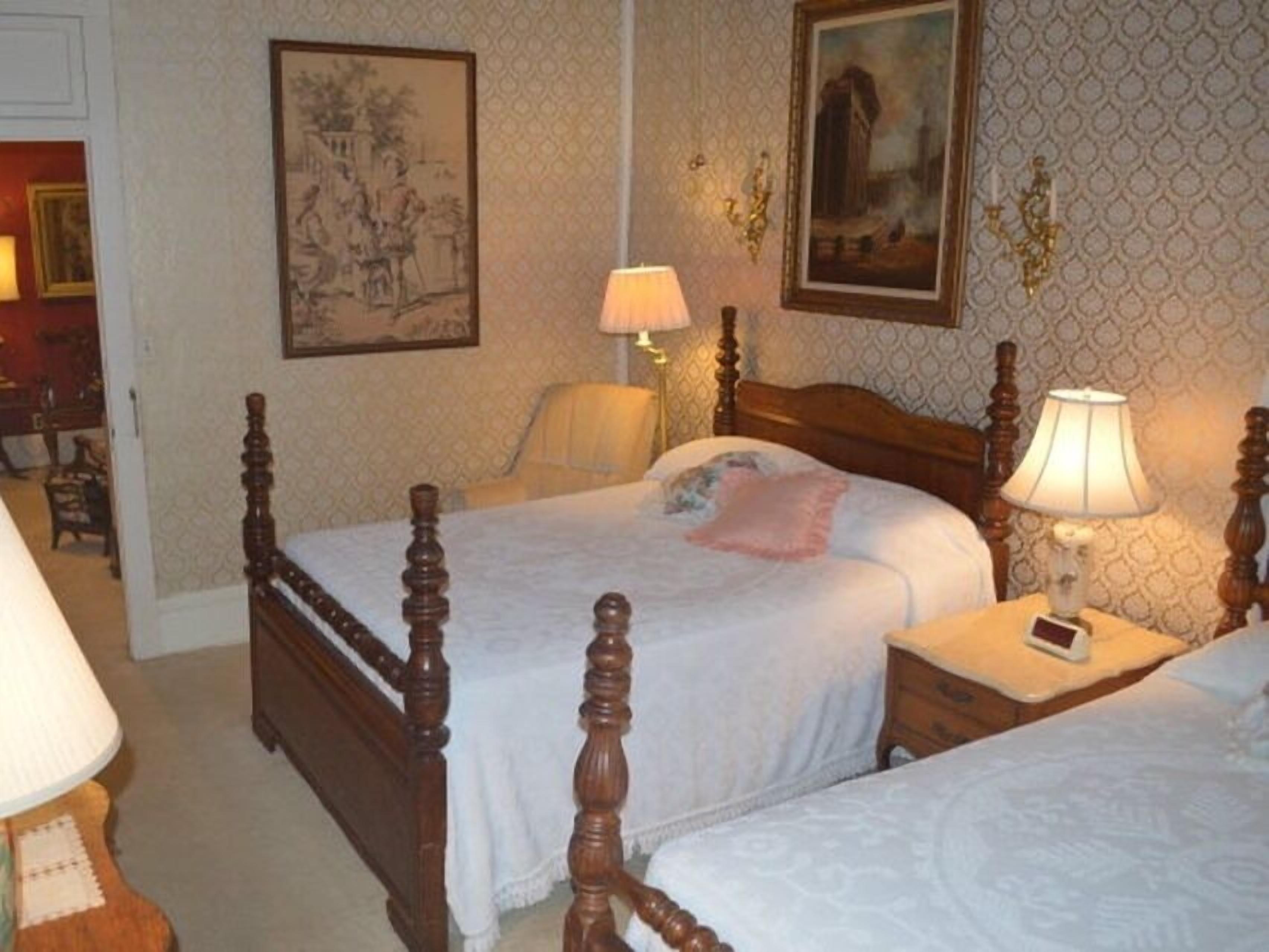 Une chambre avec deux lits en bois, une table de chevet avec une lampe et une lampe fixée au mur.