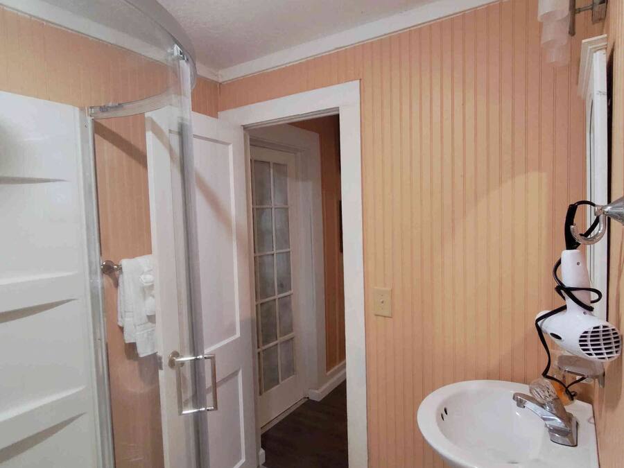 Ein Badezimmer mit Duschkabine aus Glas, Waschbecken und einem Handtrockner sowie einem Handtuchhalter.