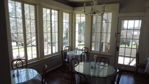 A dining area with round tables, wooden chairs, and large windows offering views of the outdoors. - Franklin Terrace Bed and Breakfast (Franklin)