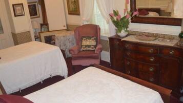 A hotel room with two beds, a wooden dresser, a chair, and a mirror.