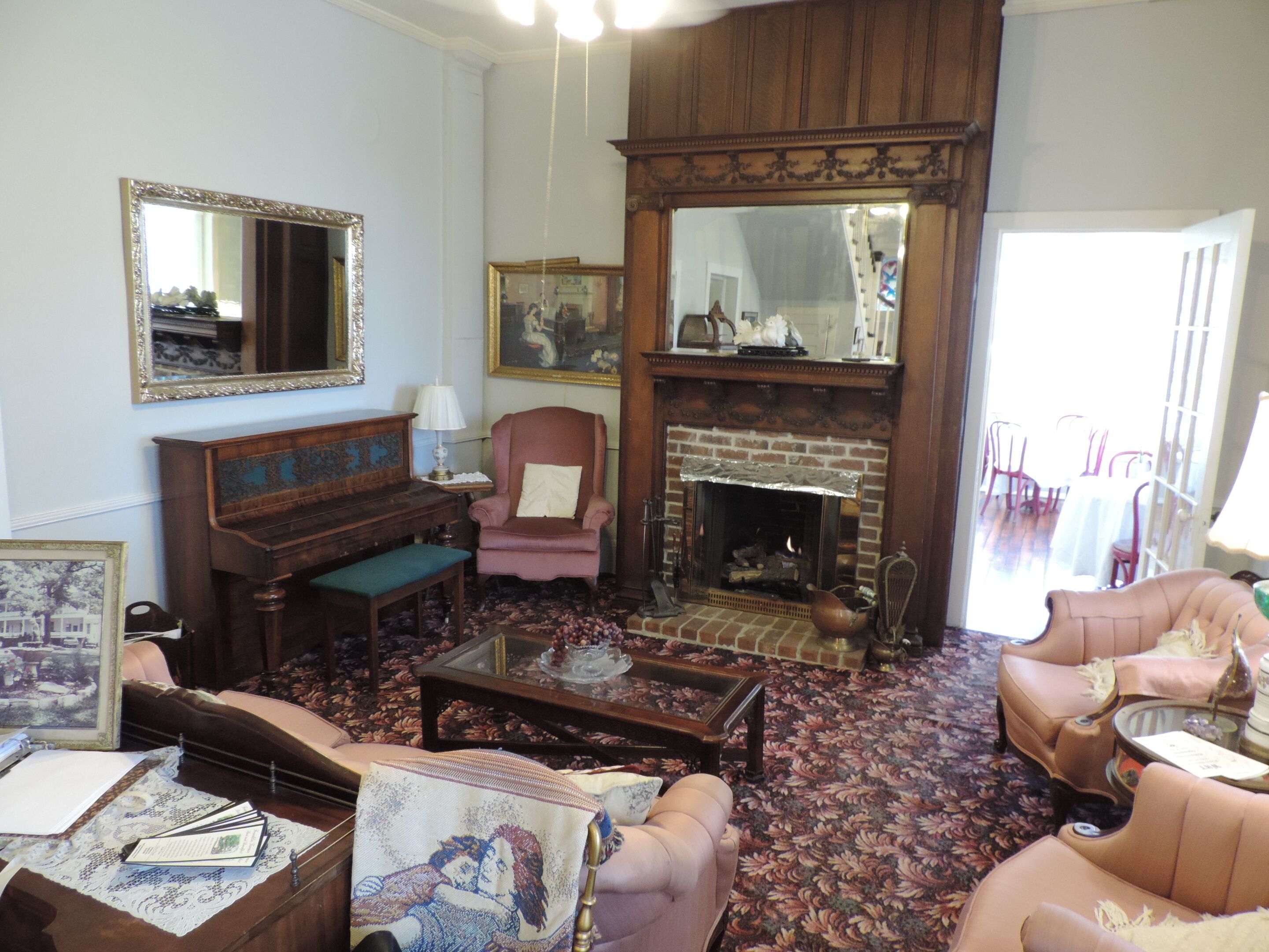 A traditional living room with a fireplace, a piano, and comfortable seating.