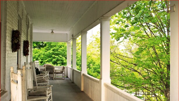A covered porch with white columns and a view of lush green trees. - Franklin Terrace Bed and Breakfast (Franklin)