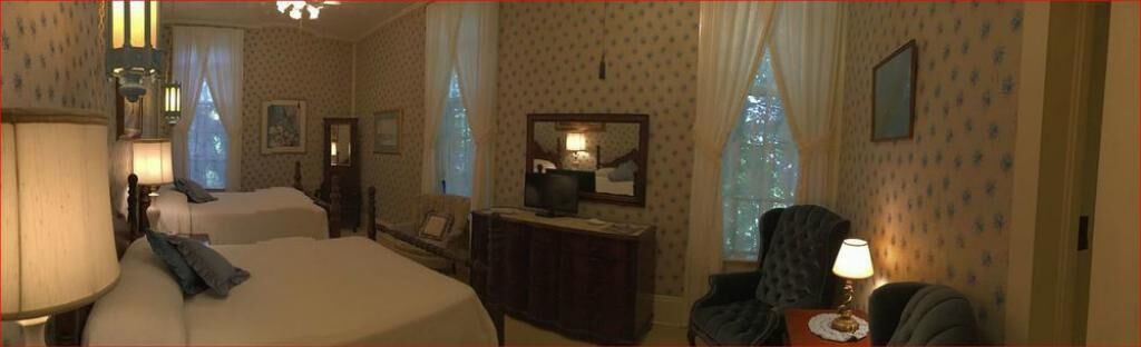 A hotel room with two beds, a dresser, a chair, and a desk with a lamp.