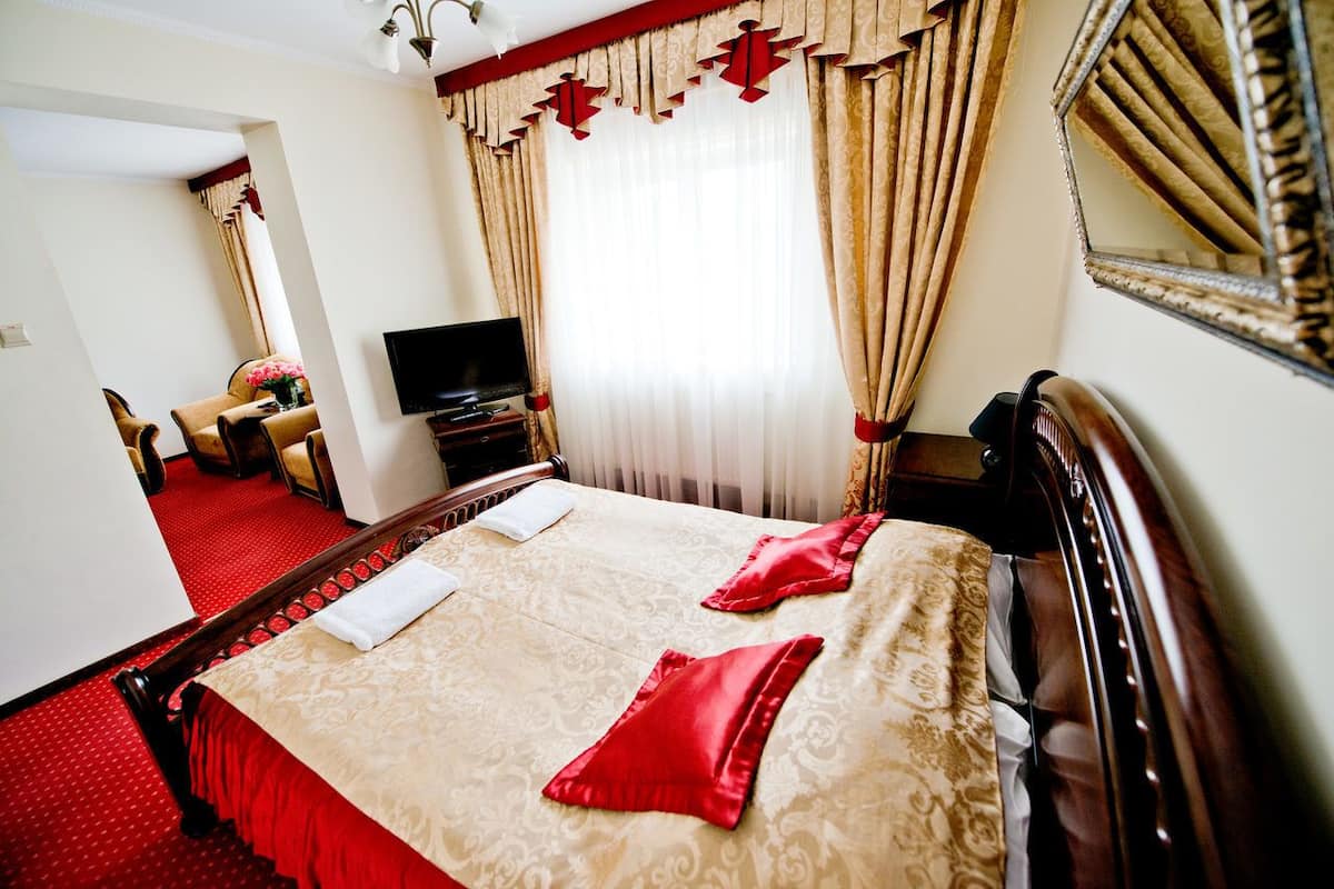 Una habitación de hotel con una cama grande, televisión y espejo.