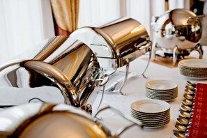 A table set with multiple stacks of white plates and a row of golden spoons. - Hotel Groman (Raszyn)