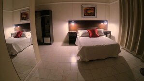 A hotel room with two beds, a large mirror, a wardrobe, and a painting on the wall. - Eclat Suites (Villa Mercedes)