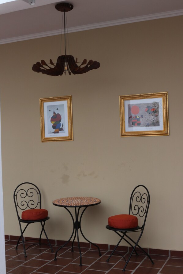 A room with two chairs and a small table, a ceiling fan, and two framed artworks on the wall. - Eclat Suites (Villa Mercedes)