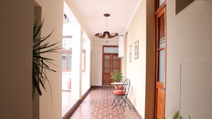 A corridor with a tiled floor, a wooden door, and a table with chairs. - Eclat Suites (Villa Mercedes)