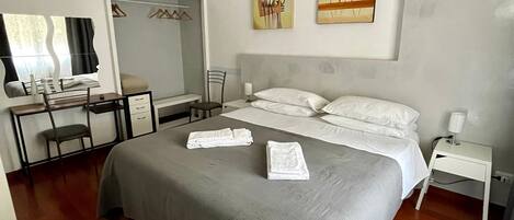 A bedroom with a bed, a desk, and a chair. There are towels on the bed.