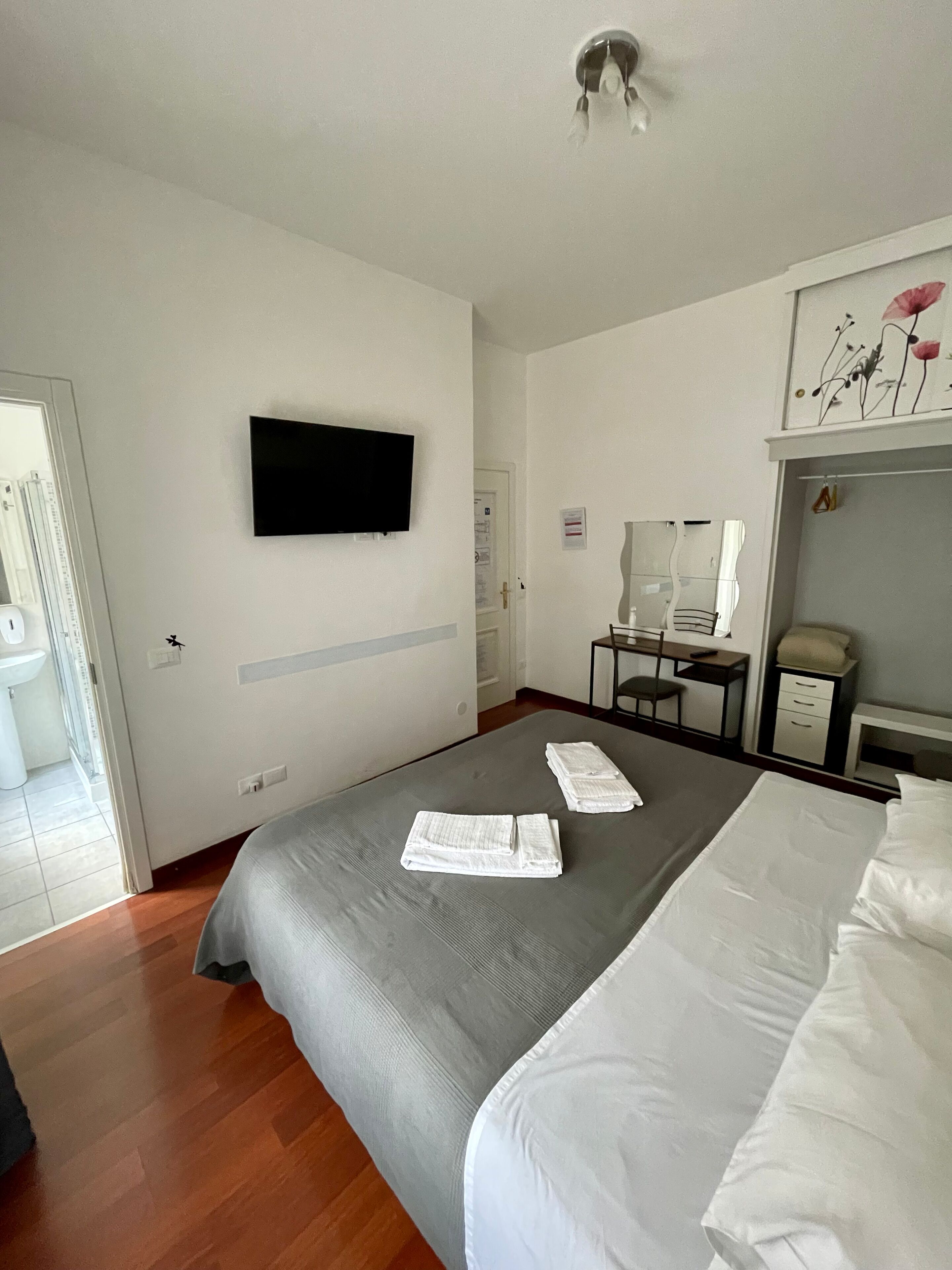 Una habitación de hotel con cama, escritorio, silla, televisor y armario.