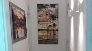 A hallway with wooden flooring, white walls, and two framed pictures. - Garden of Rome Guesthouse (Rome)
