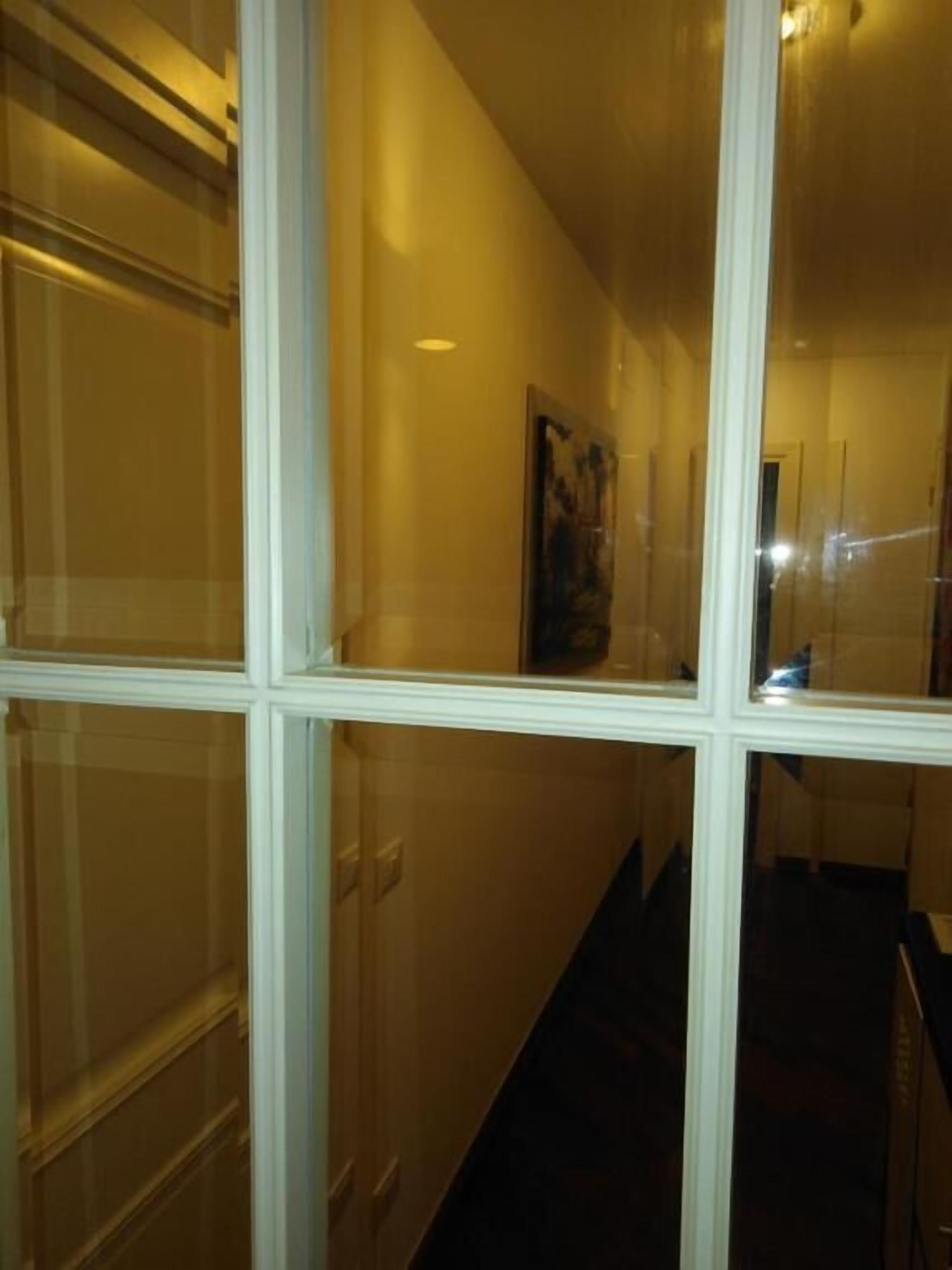 A hallway with a glass partition and a door.