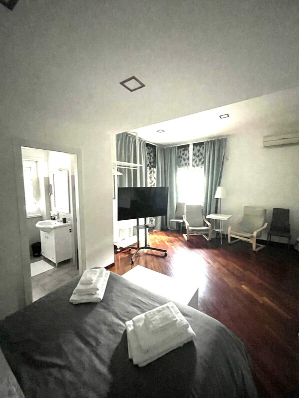 A hotel room with a bed, a TV, a desk, a chair, and a window with curtains. - Garden of Rome Guesthouse (Rome)
