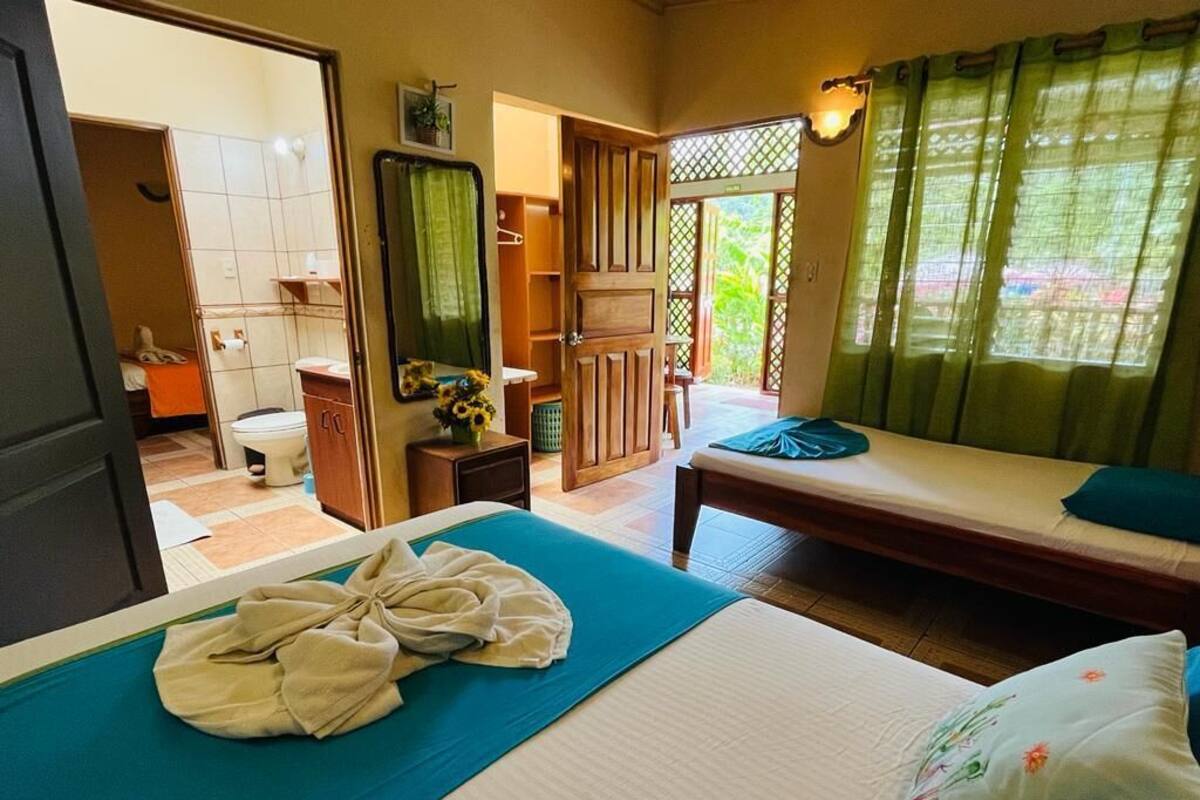 Ein Hotelzimmer mit Bett, kleinem Tisch, Stuhl, Bad und Blick ins Freie.