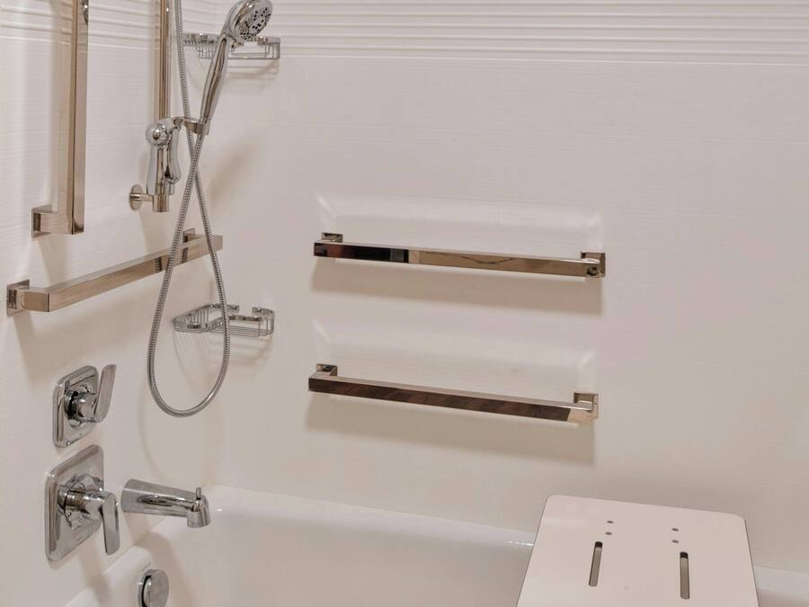 Een moderne badkamer met een bad, douchetuit, ingebouwd toilet en een klein plankje.