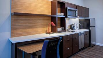 Une cuisine moderne avec des meubles en bois, un four à micro-ondes, un réfrigérateur, une machine à café et une lampe de bureau rouge.