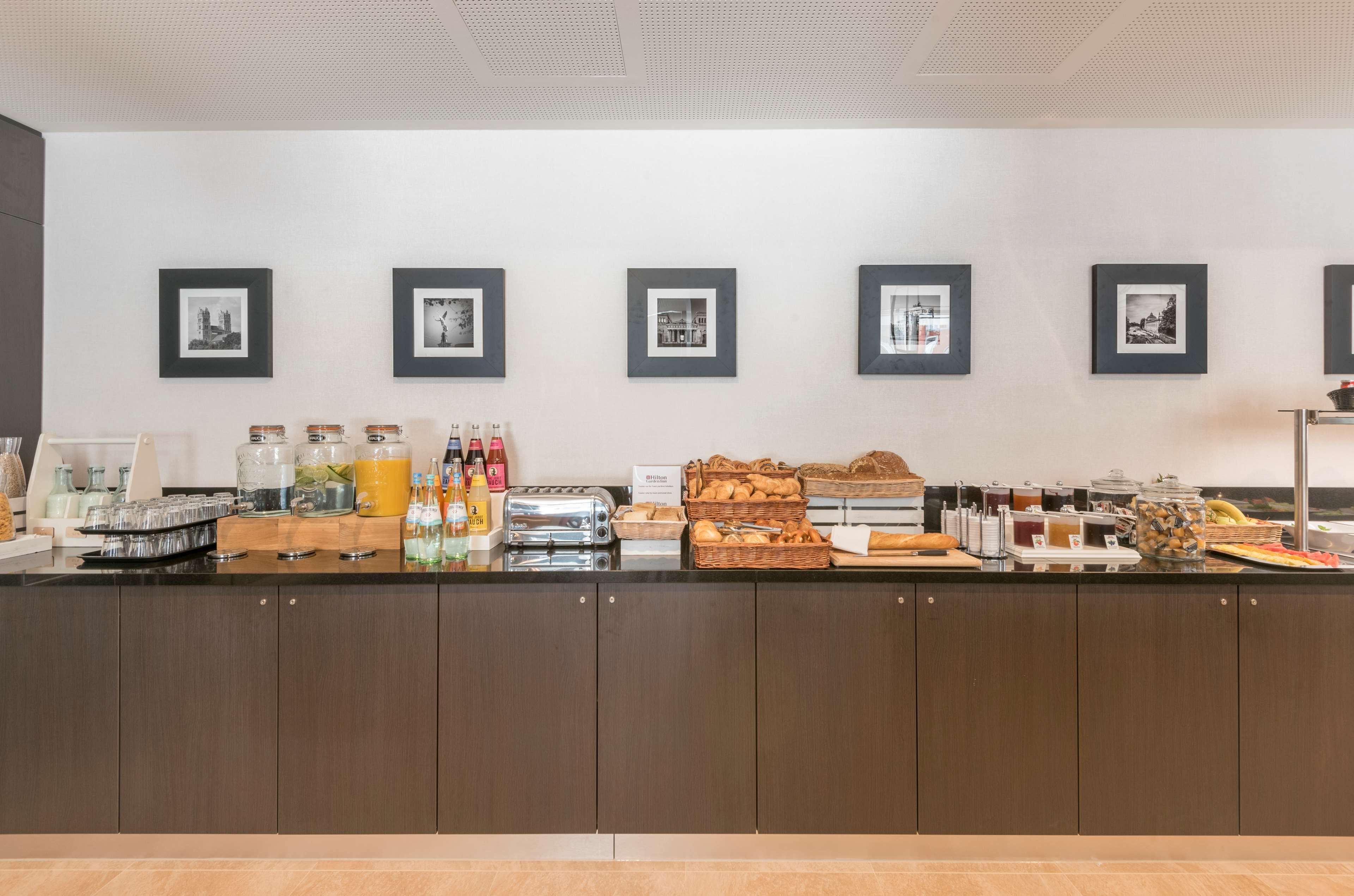 A buffet counter with various food items and beverages, framed pictures on the wall, and a clean, modern design.