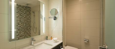 A modern bathroom with a large mirror, a sink, a toilet, and a shower area.