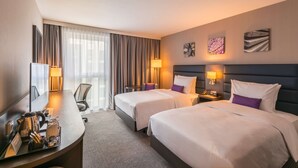 Hotellihuoneessa on kaksi sänkyä, työpöytä ja tuoli. Työpöydällä on lamppu, kahvinkeitin ja puhelin.