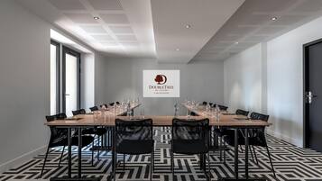 A conference room with a long table, chairs, water bottles, and a logo on the wall.