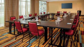 A conference room with a long table, red chairs, and a colorful striped carpet.