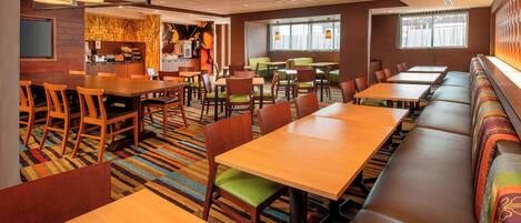 Un restaurante con varias zonas de comedor, incluyendo cabinas y mesas con sillas.