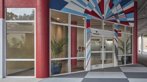 A modern building with large glass windows, a red and blue geometric wall design, and a central revolving door. - TownePlace Suites by Marriott Tampa South (Tampa)