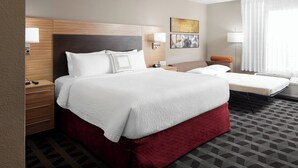 A hotel room with a large bed, a smaller bed, a desk, and a chair. There are wall-mounted lamps and a painting on the wall. - TownePlace Suites by Marriott Tampa South (Tampa)