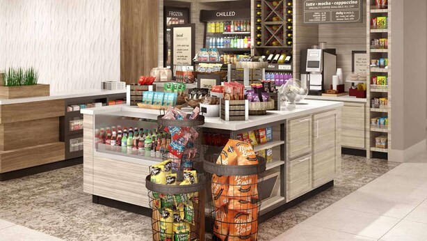 Un supermarché moderne doté d’un présentoir central, de rayons réfrigérés et d’un bar à café.