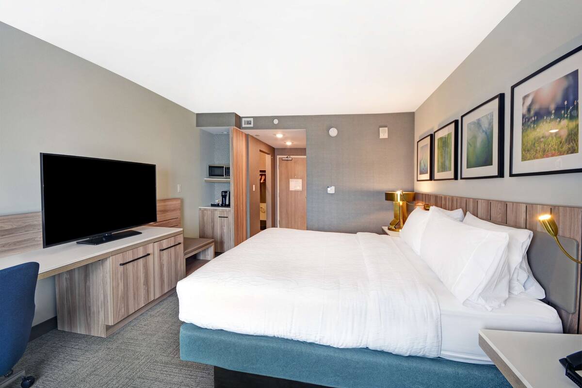 A hotel room with a large bed, a flat-screen TV, a desk, and a wardrobe.