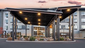 A hotel entrance with a covered walkway, large windows, and a sign for 'Hotel Pepper Pizza'. - Hotel Peppertree Bend, BW Premier Collection (Bend)
