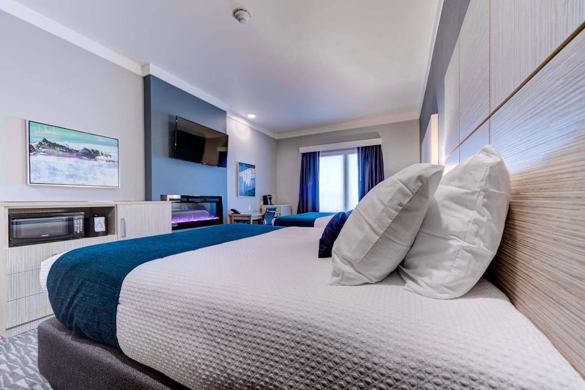 Une chambre d’hôtel moderne dotée d’un grand lit, d’une télévision à écran plat, d’un four à micro-ondes et d’un bureau avec une chaise.