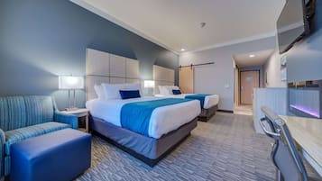 A hotel room with a large bed, two bedside tables, a sofa, a desk, and a TV.