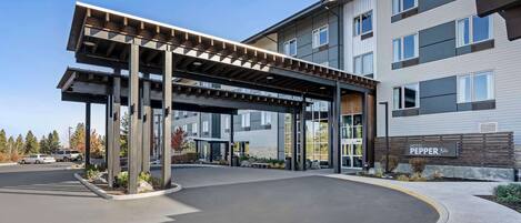 A hotel entrance with a covered walkway, a parking area, and a sign reading "HOTEL PEPPER".