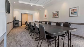 A conference room with a long table and chairs, a flat-screen TV, and artwork on the walls.