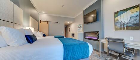 A hotel room with a large bed, a desk, and a chair.
