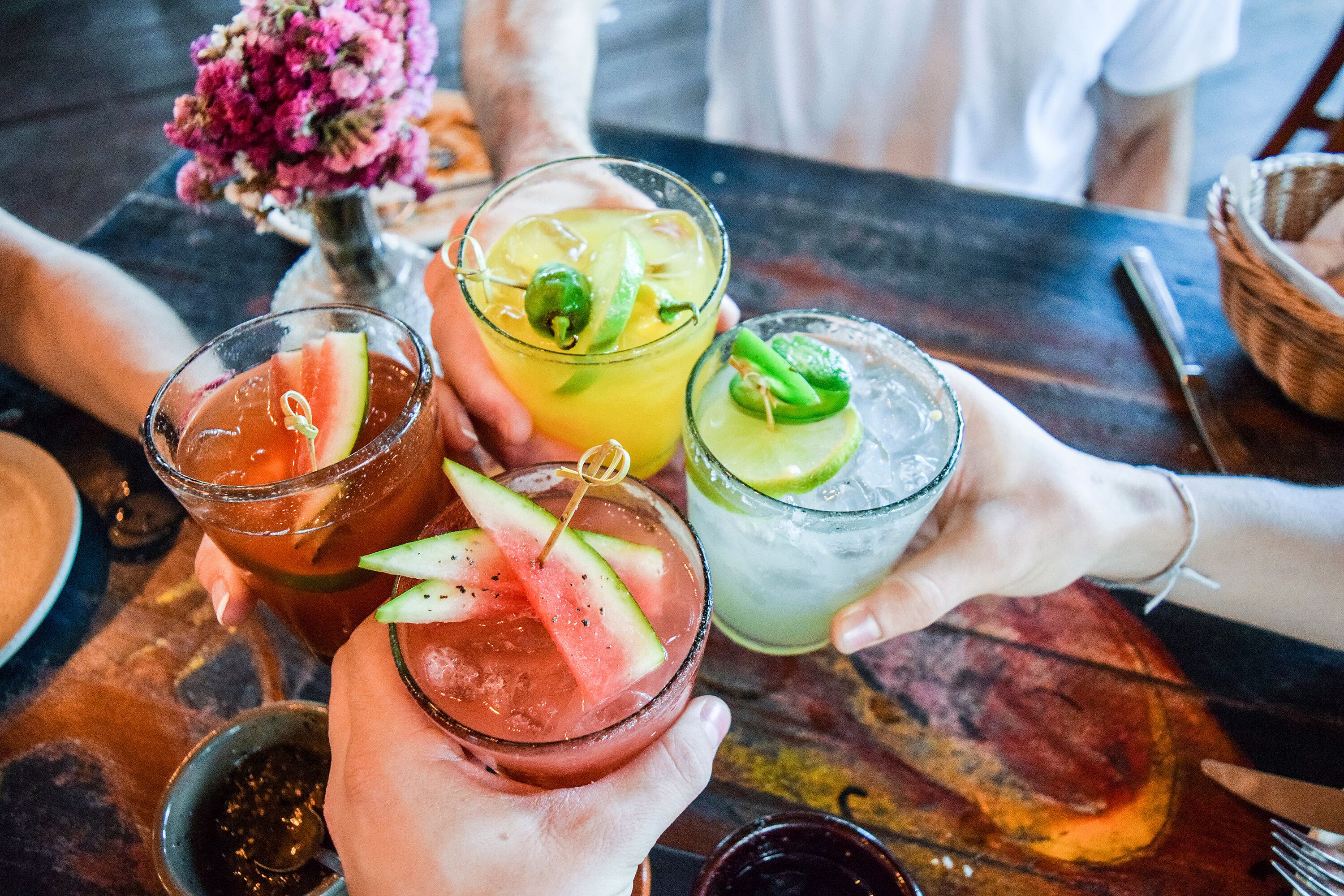 A table with three drinks, each garnished with different fruits.