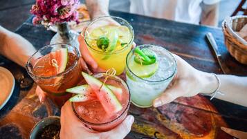 A table with three drinks, each garnished with different fruits.