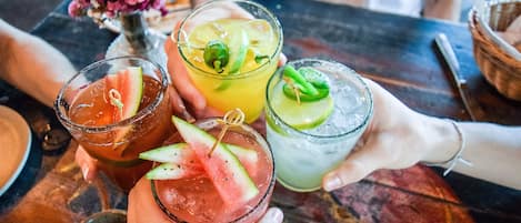 A table with three drinks, each garnished with different fruits.