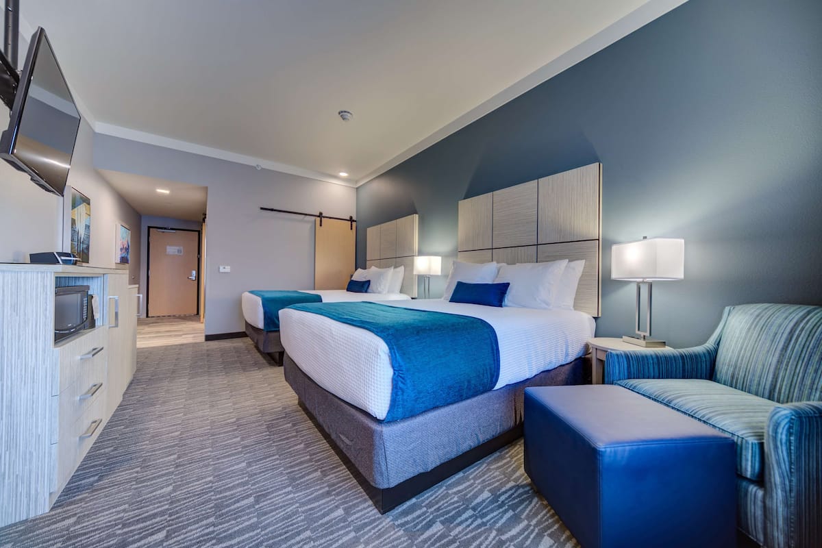 Une chambre d’hôtel avec deux lits, un bureau, une chaise et un téléviseur.