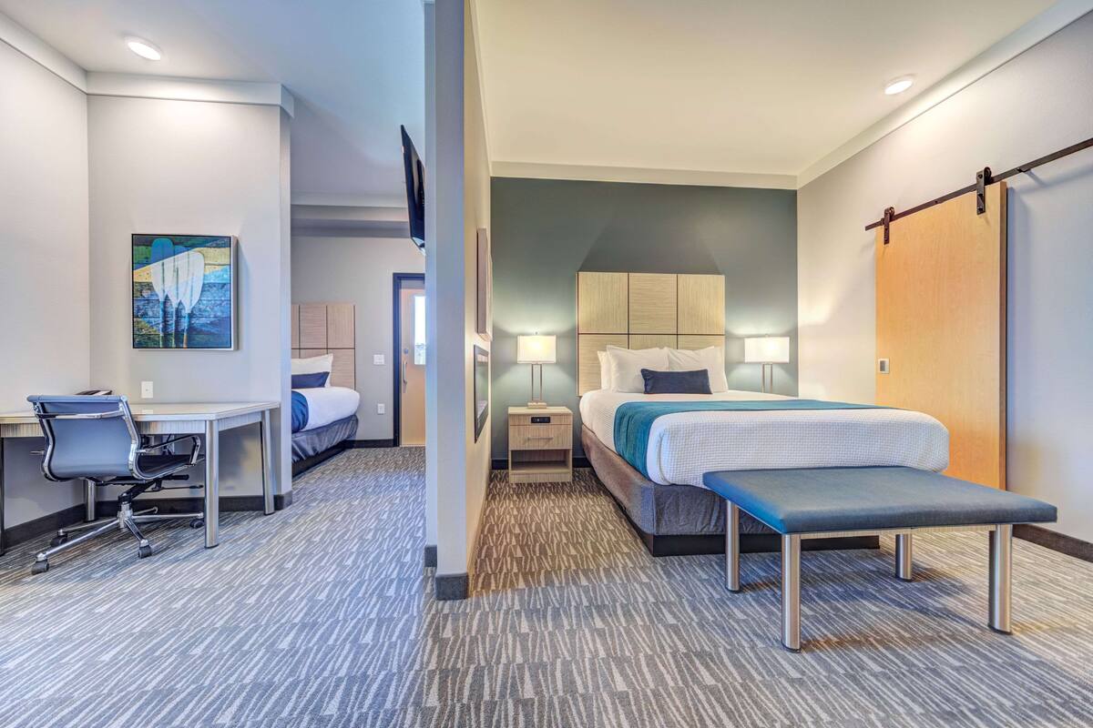 Une chambre d’hôtel avec un lit, un bureau, une chaise et un banc.