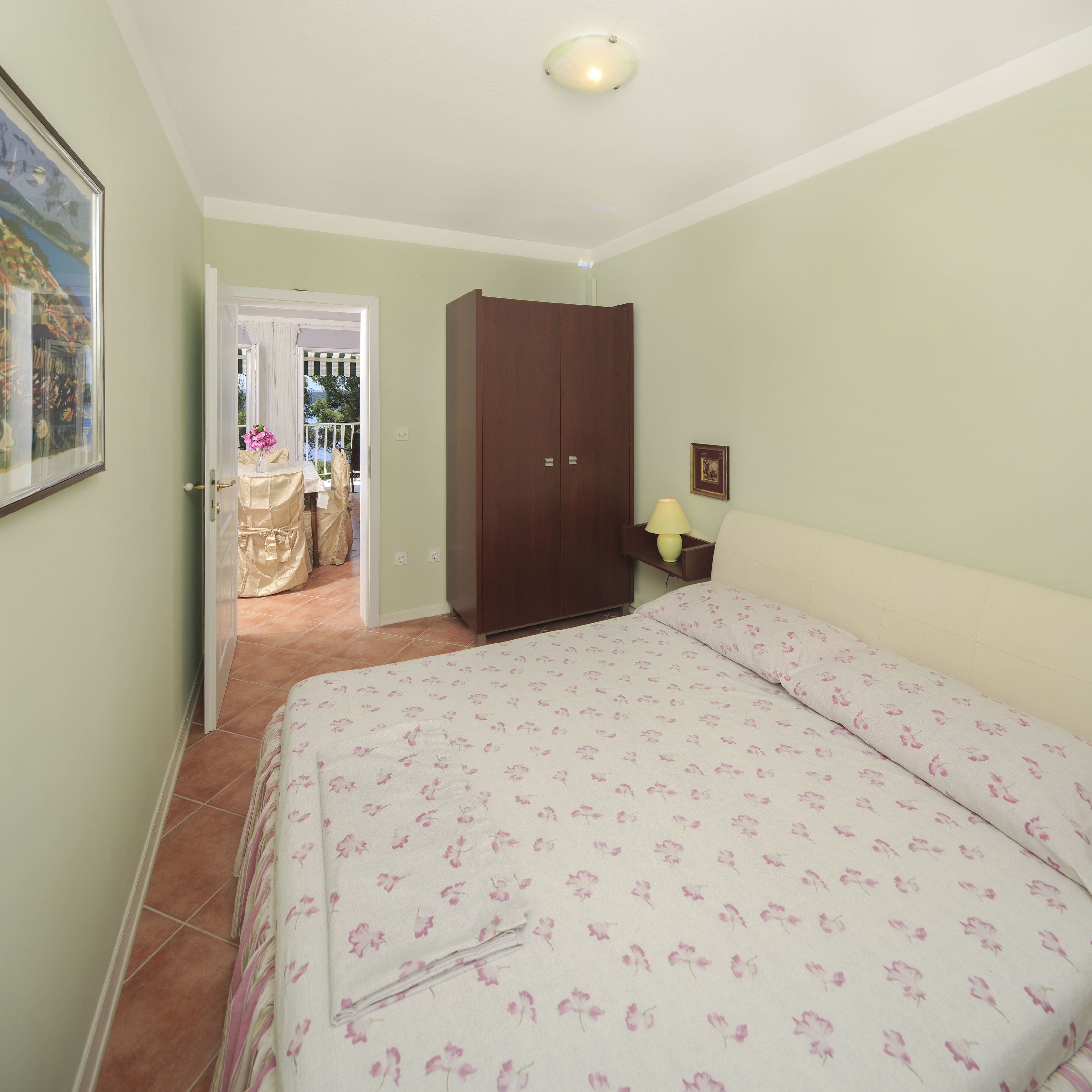 A bedroom with a bed, a wardrobe, a nightstand, and a door leading to a balcony.