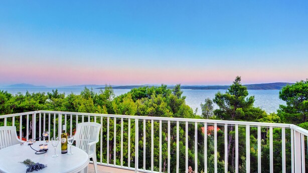 A balcony with a white railing overlooking a body of water and greenery. - Villa Tamara (Jelsa)