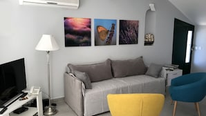 A living room with a grey sofa, a yellow armchair, a blue armchair, a flat-screen TV, a lamp, and artwork on the wall. - Villa Tamara (Jelsa)