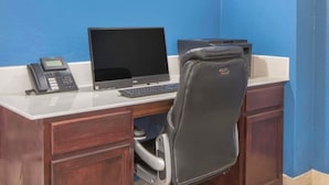 A desk with a computer, phone, and printer in a room with blue walls.