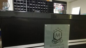 En receptionsdisk med et skilt for Maxy's Inn, der viser et logo med en stjerne og et 'M'.