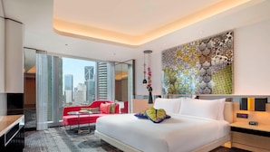A modern hotel room with a large bed, a red sofa, a city view, and a decorative wall piece. - W Kuala Lumpur (Kuala Lumpur)