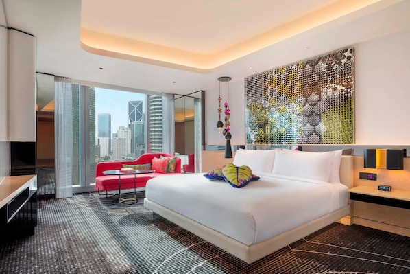 A modern hotel room with a large bed, a red sofa, a city view, and a decorative wall piece. - W Kuala Lumpur (Kuala Lumpur)